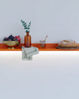 6-inch-deep Mini Mod floating aluminum shelf in orange finish, shown as a compact modular display shelf.