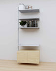 Modular media shelving extension with satin shelves and satin vertical post, with Casting Light wood cabinet storage, one bay, 31-inch shelf width, shown with open shelf levels.