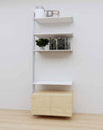 Modular media shelving extension with black shelves and white vertical post, with Tea for Two wood cabinet storage, shown with open shelf levels.